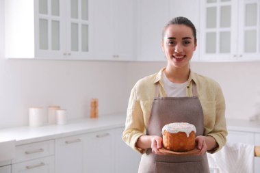 Geleneksel Paskalya pastası olan genç bir kadın mutfakta, mesaj için yer var.