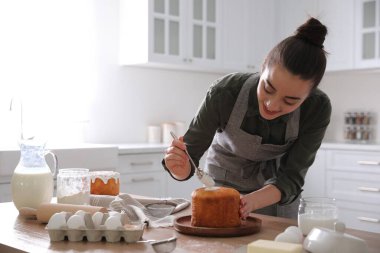 Genç bir kadın geleneksel paskalya pastasını mutfakta jöleli dekore ediyor. Metin için boşluk