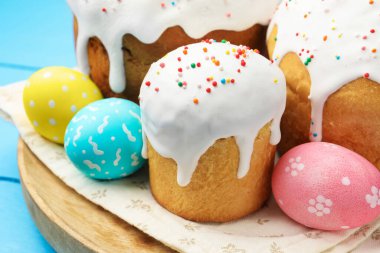 Lezzetli paskalya pastaları ve yumurtalar mavi ahşap masada, yakın plan.