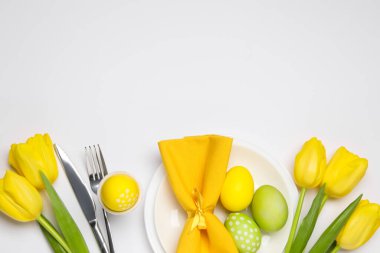 Paskalya kutlaması. Lale çiçekli şenlik masası, beyaz arka planda boyanmış bıldırcın yumurtaları, düz yatış. Metin için boşluk