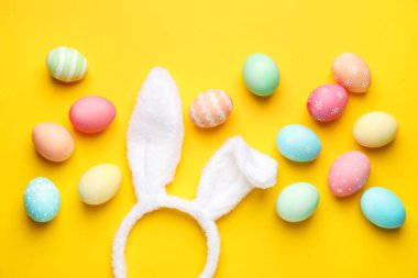 Mutlu Paskalyalar. Sevimli tavşan kulakları ve sarı arka planda boyanmış yumurtalar.
