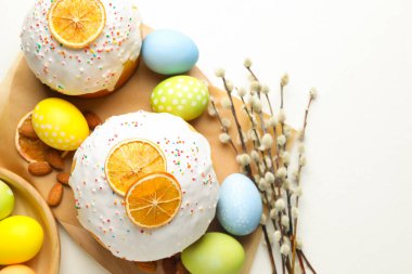 Lezzetli Paskalya pastaları, boyanmış yumurtalar ve söğüt dalları beyaz masada, düz bir şekilde. Metin için boşluk