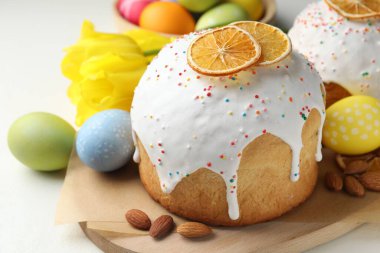 Lezzetli Paskalya pastaları, laleler ve beyaz masaya boyanmış yumurtalar, yakın plan.