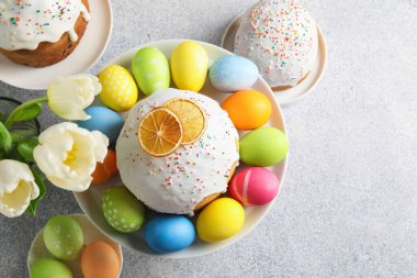 Lezzetli Paskalya pastaları, laleler ve açık gri masaya boyanmış yumurtalar. Metin için boşluk