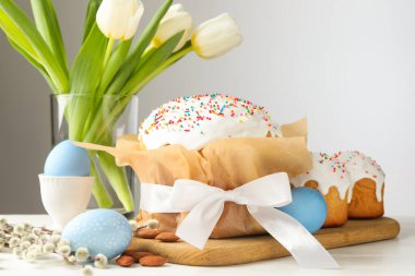 Lezzetli Paskalya pastaları, beyaz ahşap masada boyanmış yumurta ve laleler, yakın plan.