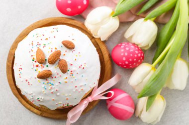 Lezzetli Paskalya pastası, açık gri masada boyanmış yumurta ve laleler, düz uzanma