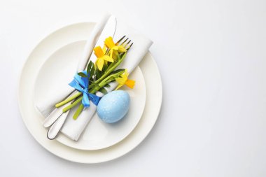 Paskalya kutlaması. Nergis çiçekleri ve beyaz arka planda boyanmış yumurta ile şenlikli masa ayarı, üst manzara. Metin için boşluk