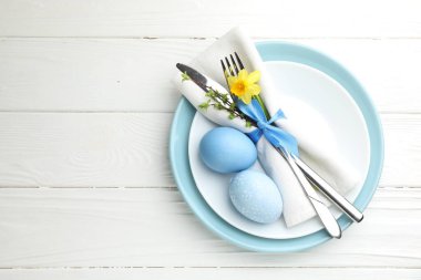 Paskalya kutlaması. Nergis çiçekli şenlik masası ve beyaz ahşap arka planda boyanmış yumurtalar, üst manzara. Metin için boşluk