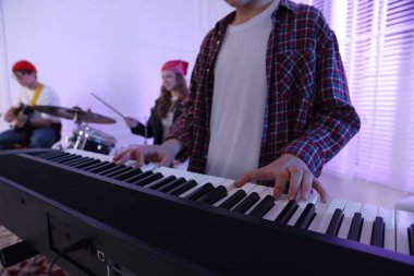 Genç müzik grubu kapalı alanda performanslarını prova ediyor, seçici odaklanma.