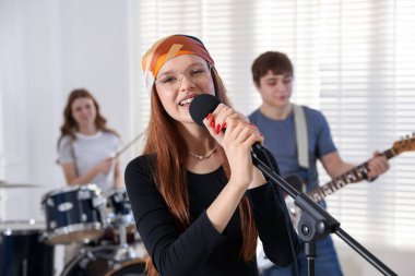 Genç müzik grubu içeride performanslarını prova ediyor.