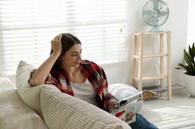 Dergisi olan kadın evdeki kanepede dinleniyor.