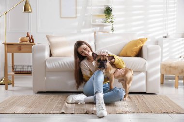 Evdeki kanepenin yanında sevimli köpeği olan bir kadın.