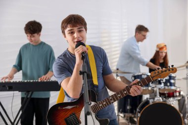 Genç müzik grubu içeride performanslarını prova ediyor.