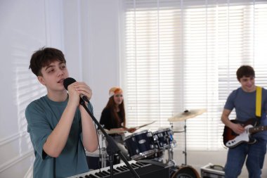 Genç müzik grubu içeride performanslarını prova ediyor.