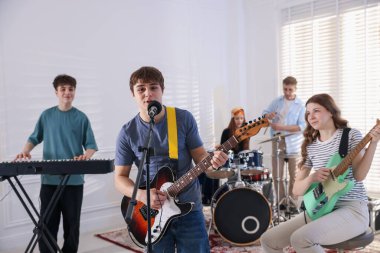 Genç müzik grubu içeride performanslarını prova ediyor.