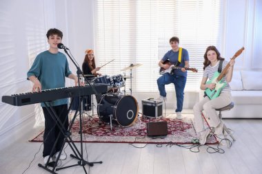 Genç müzik grubu içeride performanslarını prova ediyor.