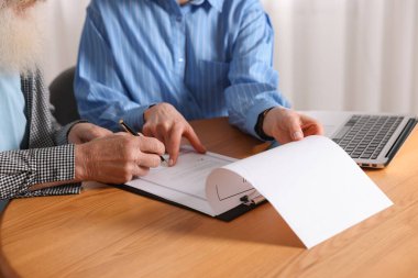 Noter, son vasiyet ve vasiyetnamenin nerede imzalanacağını gösteriyor. Ofisteki ahşap masada, yakın plan.