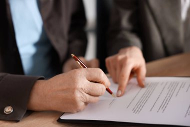 Noter, son vasiyet ve vasiyetnamenin nerede imzalanacağını gösteriyor. Ofisteki ahşap masada, yakın plan.