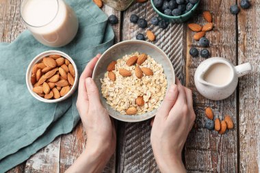 Yulaf gevreği, fındık, badem sütü ve böğürtlenli kadın ahşap masada.