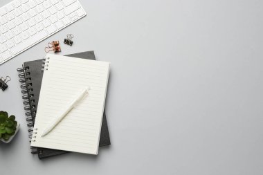 Ofis işyeri. Defterler, kalem ve klavye gri masada, düz yerde. Metin için boşluk