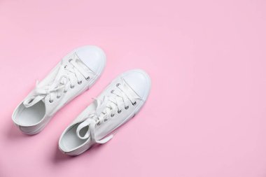 Pembe arka planda şık bir çift spor ayakkabı, üst manzara. Metin için boşluk