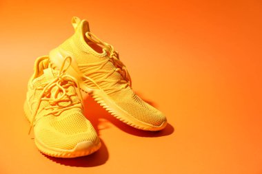 Turuncu arka planda şık bir çift spor ayakkabı, yakın plan. Metin için boşluk