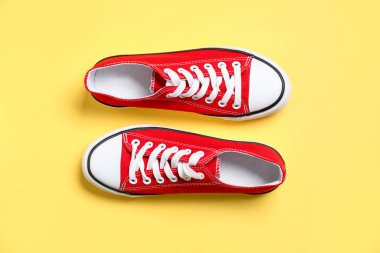 Sarı arka planda şık bir çift spor ayakkabı, üst manzara.