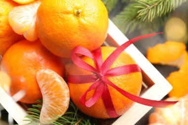 Mandalinalar sandıkta ve köknar dalları masada, yakın plan.