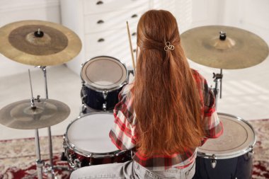 Bagetli genç kız davul çalmayı içeride, arka planda öğreniyor.