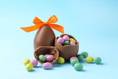 Açık mavi arka planda renkli şekerli lezzetli çikolata yumurtaları, yakın plan. Mutlu Paskalyalar