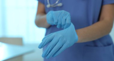 Klinikte eldiven takan bir tıp çalışanı, yakın plan. Metin için boşluk