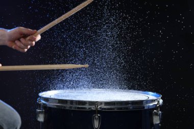 Siyah arkaplanda davul çalan bagetli adam, yakın plan