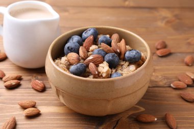 Yulaf gevreği, badem sütü, fındık ve yaban mersini ahşap masada, yakın plan.