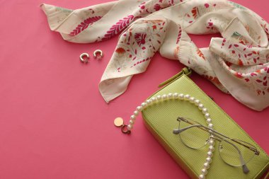 Pembe arka planda şık bir mendil, çanta ve diğer aksesuarlar. Metin için boşluk