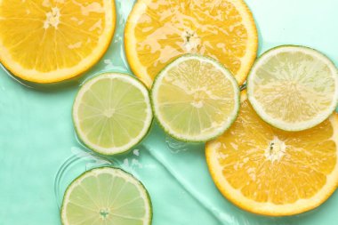 Turkuaz arka planda sudaki narenciye dilimleri, düzlük.