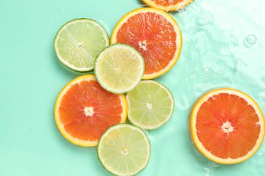 Turkuaz arka planda sudaki narenciye dilimleri, düzlük.