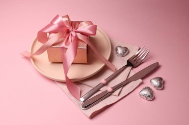 Pembe arka planda hediyeli şık masa ayarı, yakın plan.