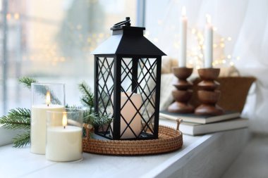 Güzel Noel feneri, yanan mumlar, köknar dalları ve pencere pervazındaki diğer dekorlar, yakın çekim.