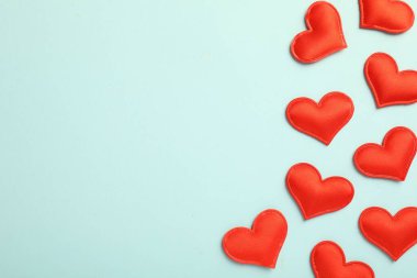 Sevgi. Açık mavi arka planda kırmızı dekoratif kalpler, düz yatış. Metin için boşluk