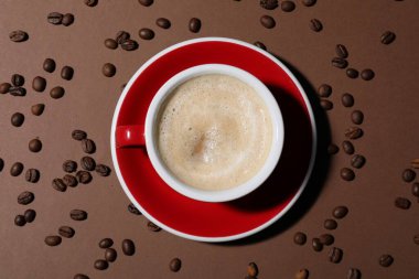 Kahverengi arka planda bir fincan aromatik kahve ve fasulye.