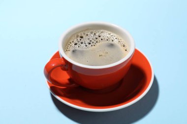 Açık mavi arka planda bir fincan aromatik kahve, yakın plan.