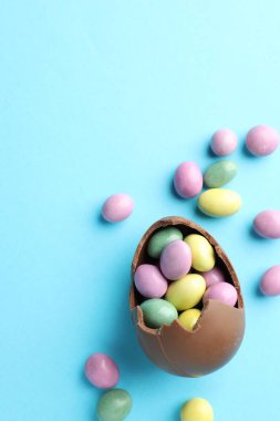 Paskalya kutlaması. Açık mavi arka planda şekerli kırık çikolata yumurtası, düz. Metin için boşluk
