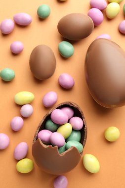 Soluk turuncu arka planda çikolatalı Paskalya yumurtası ve şekeri.