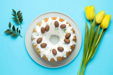 Lezzetli Paskalya pastası, güzel laleler ve açık mavi arka planda yeşil yapraklar.