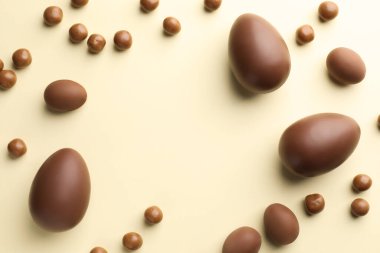 Bej arka planda çikolatalı Paskalya yumurtaları ve şekerler, düz konum. Metin için boşluk