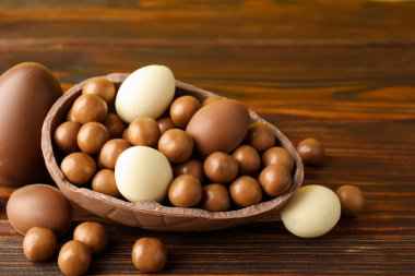 Ahşap masada şekerli çikolatalı yumurtalar, yakın plan. Mutlu Paskalyalar