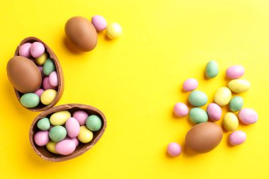 Sarı arka planda renkli şekerlemeli leziz çikolatalı yumurtalar. Mutlu Paskalyalar