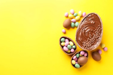 Mutlu Paskalyalar. Sarı arka planda renkli şekerlemeli leziz çikolatalı yumurtalar. Metin için boşluk