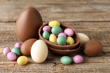 Ahşap masada renkli şekerlemeli lezzetli çikolata yumurtaları, yakın plan. Mutlu Paskalyalar