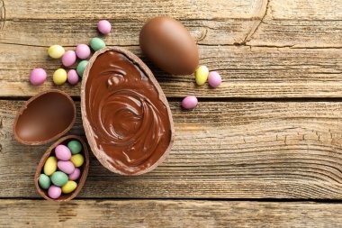 Mutlu Paskalyalar. Tahta masanın üzerinde renkli şekerlemeli leziz çikolatalı yumurtalar, düz yatak. Metin için boşluk